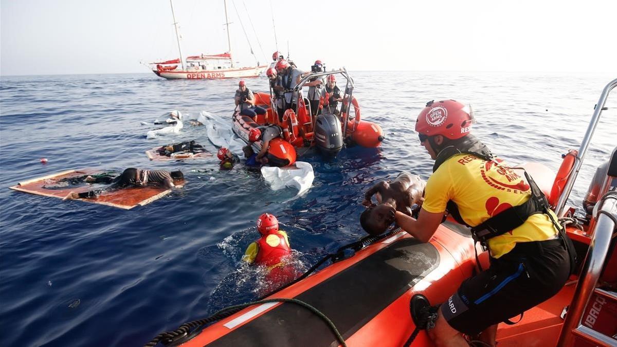 Un miembro de Proactiva Arms saca un cadáver del agua mientras sus compañeros rescatan a una mujer del agua