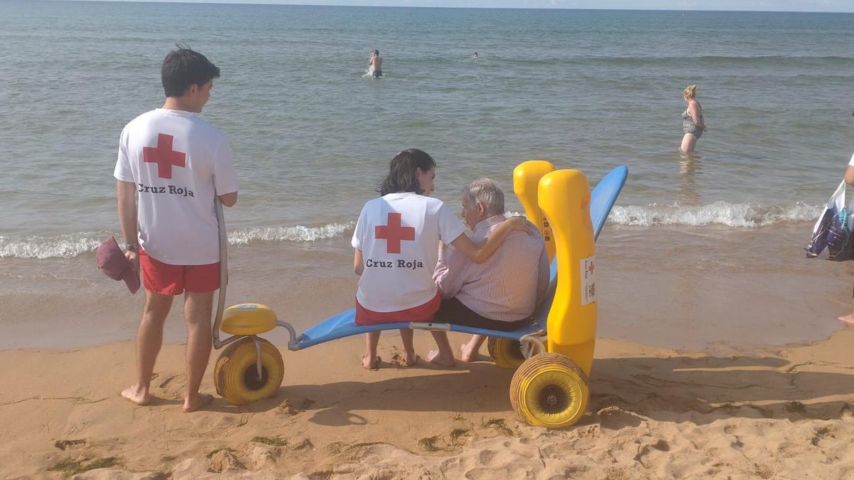 Voluntarios de Cruz Roja en Rodiles ayudan a una persona con movilidad reducida.