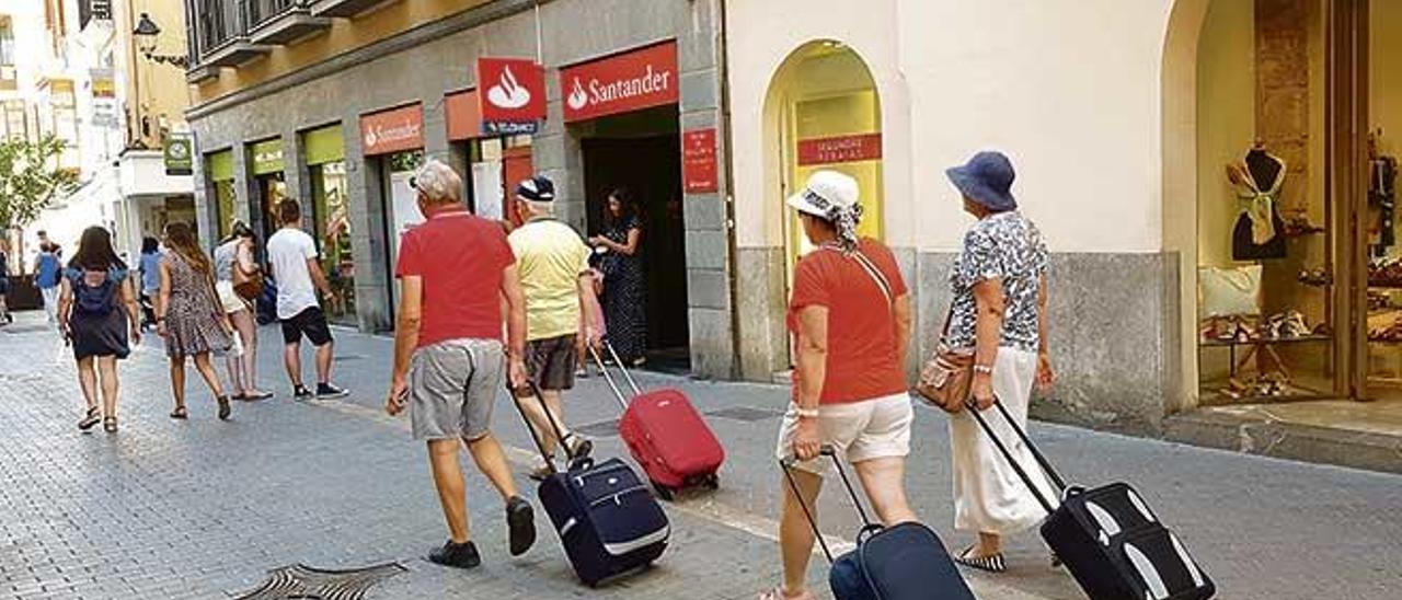Turistas arrastrando maletas en busca de su alojamiento.