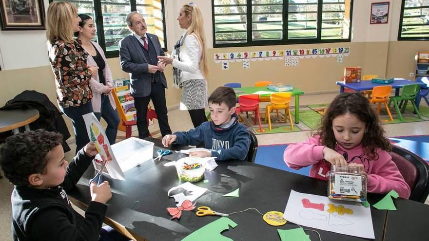 Niños fabricando adornos de Navidad, con el alcalde al fondo.