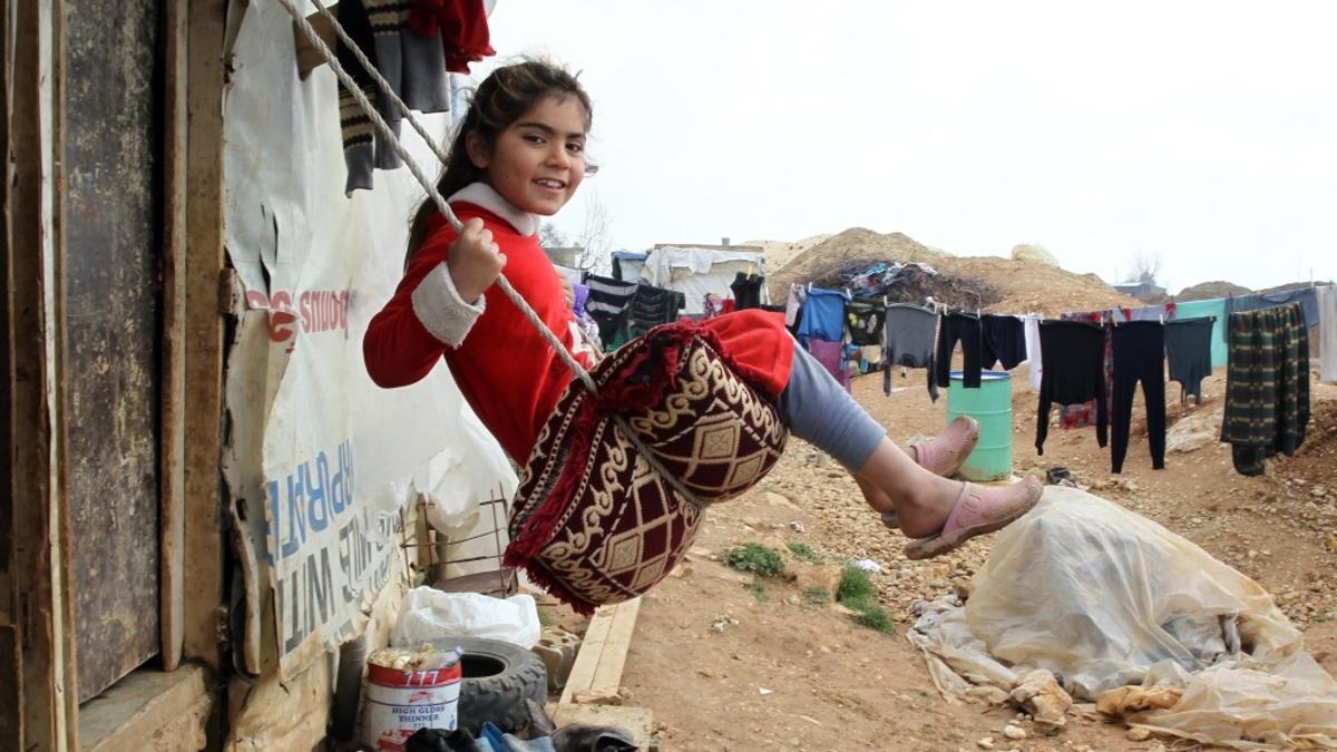 Una niña siria se columpia en un campamento de refugiados.