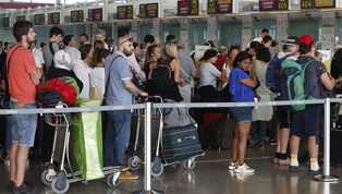 Pasajeros de un vuelo hacen cola para facturar